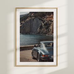 a car parked next to the ocean in front of a cliff