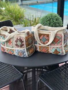 two crocheted purses sitting on top of a table next to a potted plant