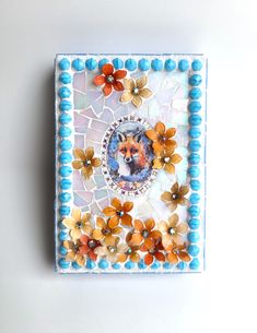 a small square tile with flowers and a dog's face in the center, on a white background