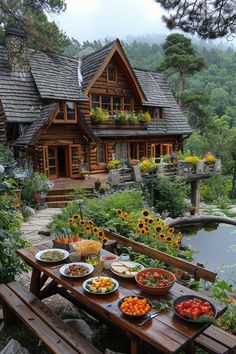 a wooden table topped with plates of food next to a house covered in sunflowers