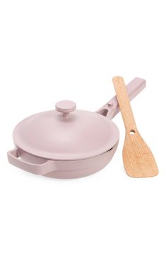 a pink pan with a wooden spatula next to it on a white table top