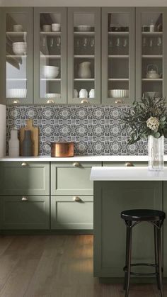 a kitchen with green cabinets and stools in front of the counter top, along with two black bar stools