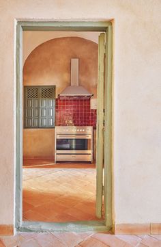 an open door leading to a kitchen with a stove and oven in the middle of it