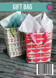 two paper bags sitting next to each other on a wooden table with the words gift bag written