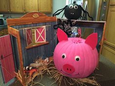 a pink pig sitting on top of a pile of hay next to a doll house