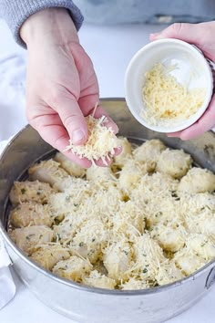 someone is sprinkling parmesan cheese on top of some meatballs in a pan