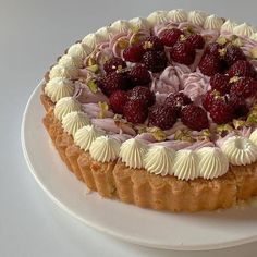 a white plate topped with a cake covered in whipped cream and raspberry topping