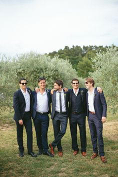 a group of men standing next to each other on top of a lush green field