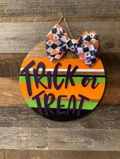 a wooden sign that says trick or treat with a bow on it's head