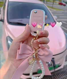 a person holding up a cell phone in front of a pink car with hearts on it