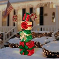 a stack of presents sitting on top of snow covered ground in front of a house