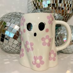 a white coffee cup with pink flowers on it and disco balls in the back ground