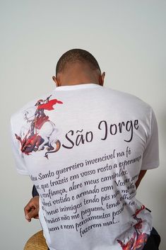 a man sitting in a chair with his back to the camera, wearing a t - shirt that says sao jorge