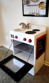 a toy stove and sink in the corner of a room with a framed picture on the wall