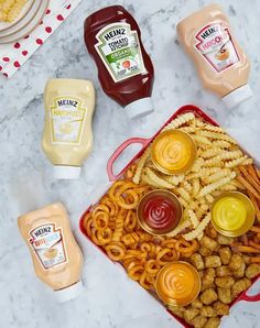 a table topped with lots of food and condiments next to bottles of ketchup