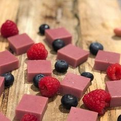 a wooden cutting board topped with raspberries and blueberries