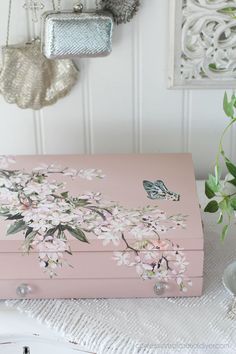 a pink suitcase sitting on top of a white table next to a vase with flowers