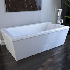 a white bath tub sitting on top of a hard wood floor next to a painting