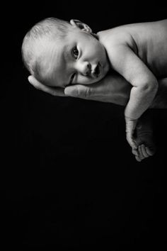 a black and white photo of a baby being held by someone's hand in the dark