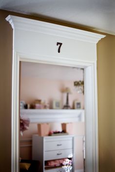 an open door with the number seven on it in front of a dresser and shelf