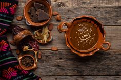 a wooden table topped with two bowls filled with chocolate and nuts next to other items