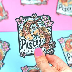 a hand holding up a sticker that says pisces