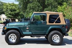 a green jeep with a tan top parked on the street