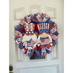 a patriotic wreath is hanging on the front door with an american flag design and two gnomes