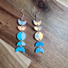 two pairs of blue and white earrings on a wooden table with a piece of wood in the background