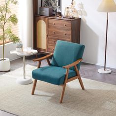 a blue chair sitting on top of a rug next to a wooden dresser and lamp