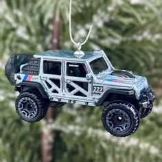 an ornament shaped like a jeep is hanging from a tree with trees in the background