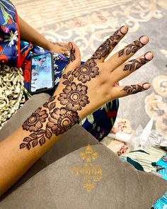 a woman's hand with henna tattoos on it and her phone in the background