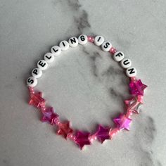 a bracelet with pink and white stars on it that says speaking us in small letters