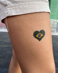 a woman's legs with a heart - shaped brazil flag tattoo on her thigh