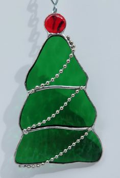 a stained glass christmas tree ornament hanging on a chain