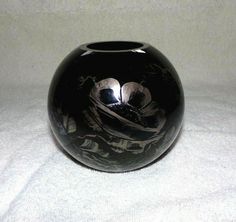 a black vase sitting on top of a white sheet