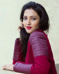 a woman sitting on the ground with her hand to her ear and looking at the camera