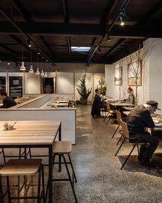 people sitting at tables in a restaurant with long counter tops and wooden chairs around them