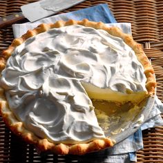 a pie with whipped cream on top sitting on a table next to a knife and fork