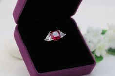 Showcased here is a 3 stone design that is perfect for ladies who love simplistic styles but in eye-catching size (in total 7.22 Ct). Delicated crafted with shimmering 925 silver set with a created Ruby centre (10mm) with 2 traingle cut on the sides. Eye-catching sparkle of this piece is absolutely breathtaking. ITEM SPECIFICATIONS Metal Type: Solid 925 Sterling Silver Metal Stamp: 925 Plating: Rhodium Plating Main Stone Dimension: Red Princess Cut 10MM Approximate Center Stone: 5 Carat Approxim Elegant Three Stone Ruby Ring Gift, Three Stone Ruby Ring Fine Jewelry Gift, Three Stone Ruby Ring As Fine Jewelry Gift, Three Stone Round Ruby Ring As Gift, Fine Jewelry Three Stone Ruby Ring Gift, Fine Jewelry Ruby Ring With Three Stones For Gift, Elegant Three Stone Ruby Ring, Three Stone Marquise Cut Diamond Ring Gift, Elegant Three-stone Ruby Ring For Wedding