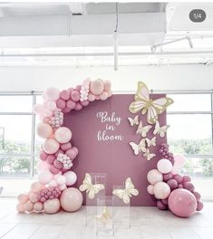 a pink and white balloon arch with butterflies on it in front of a large window