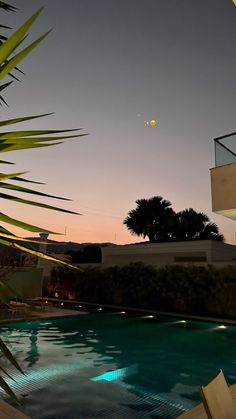 an empty swimming pool at dusk with the moon in the sky