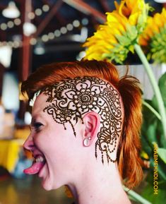 a woman with henna on her face and sunflowers in the back ground