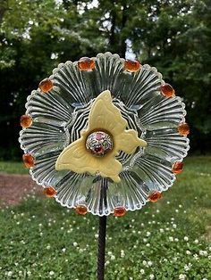 a glass flower with an orange center on a metal stand in the middle of some grass