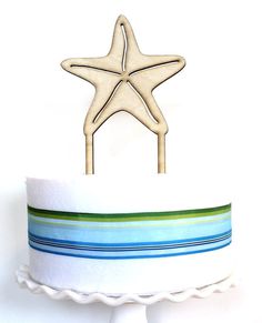 a wooden starfish on top of a cake with blue, green and white stripes