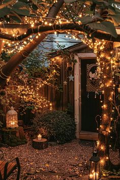 an outdoor area with lots of lights on the trees and plants around it, along with a wooden bench