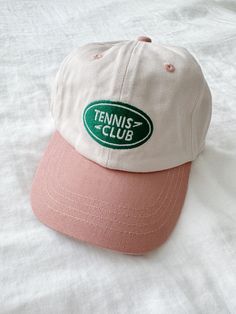 A baseball cap featuring a tennis club embroidery and an adjustable clasp for the perfect fit. Runs large recommended for ages 2+ Kitan Club Hats, White Baseball Cap For Tennis, White Tennis Baseball Cap, White Tennis Cap, Sporty Baseball Cap With Letter Print For Spring, Sporty Spring Baseball Cap With Letter Print, Sporty Snapback Hat For Tennis, Sporty Snapback Baseball Cap For Tennis, Casual Snapback Tennis Hat