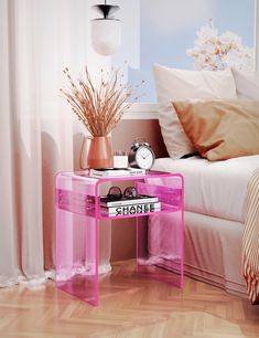 a pink table sitting on top of a hard wood floor next to a white bed