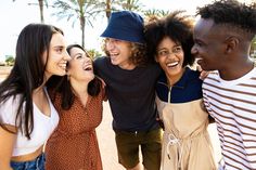 a group of young people standing next to each other on a sidewalk with palm trees in the background