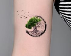 a tree with its roots in the shape of a circle tattoo on the left inner arm